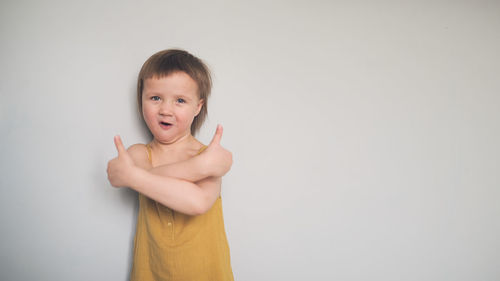 Cute child in yellow jumpsuit shows hand like, hand thumb up. light background