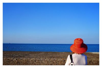 Scenic view of sea against clear blue sky woman red hat