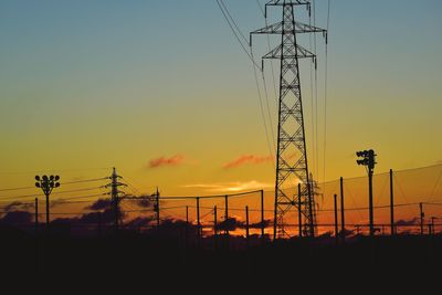 Low angle view of silhouette electricity pylon against sky during sunset