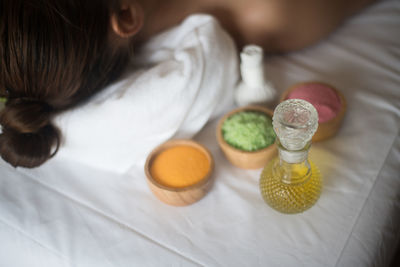 Young woman lying by spa products on massage table