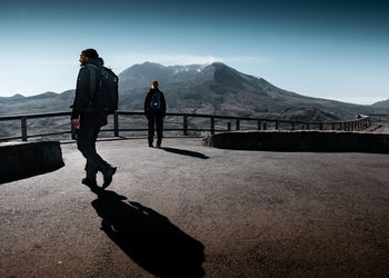 Rear view of men standing on mountain against sky