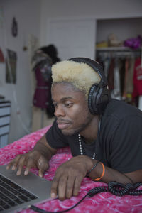 A young man wearing headphones with a laptop