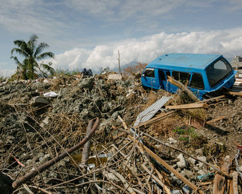 Panoramic view of abandoned cars on field against sky