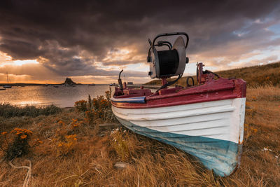 Boat moored on beach against sky during sunset