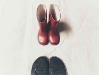 Low section of person standing by shoes on floor