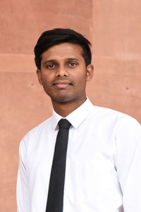 Portrait of young man standing against wall