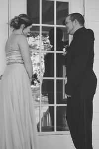 Smiling bride and groom standing by glass door