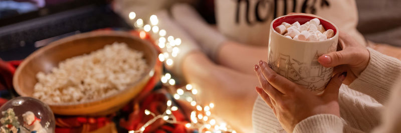 Woman drinking hot chocolate cup marshmallow in hand holding watching movie