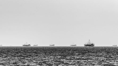 Sailboats sailing in sea against clear sky