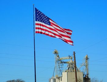 Low angle view of american flag against clear blue sky