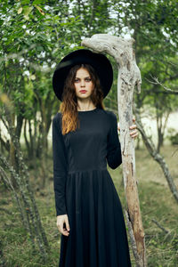 Young woman standing against tree