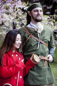 Happy young couple standing against trees