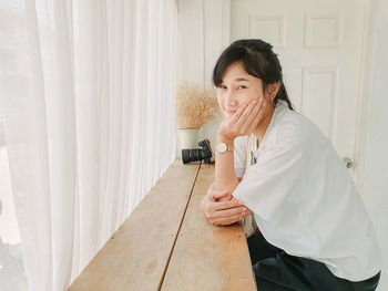 Portrait of woman standing against curtain