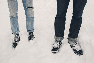 Low section of friends standing on snow covered field