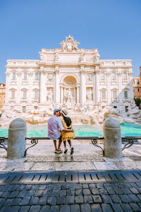 Rear view of couple sitting against historical building