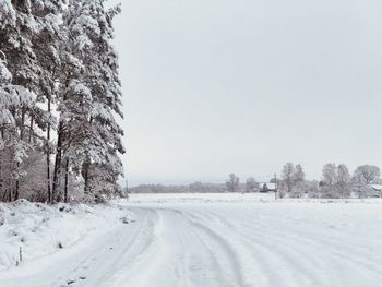 Snow covered land against clear sky during winter