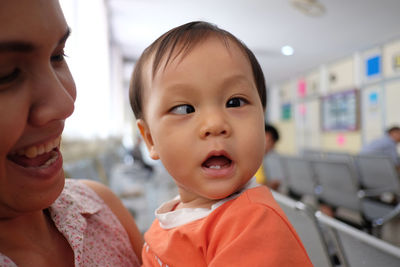 Close-up of baby boy with mother suffering from cross-eyed at hospital