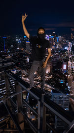 Full length of man with illuminated modern building in city at night