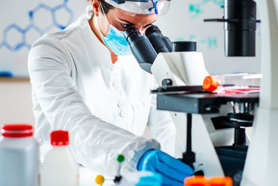 Midsection of scientist using microscope while working in laboratory