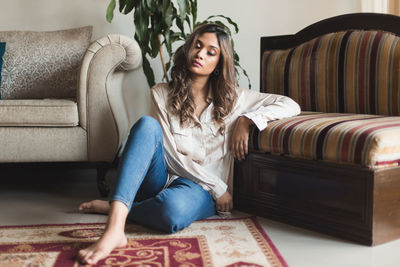 Young woman sitting on sofa at home