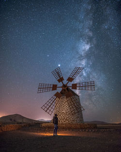 Woman with umbrella against sky at night