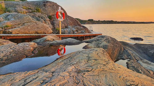 Rock formations by sea against sky during sunset