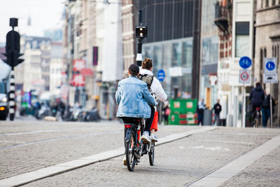 Rear view of woman riding bicycle on city street