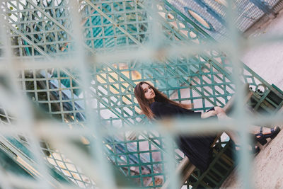 Portrait of young woman looking through fence