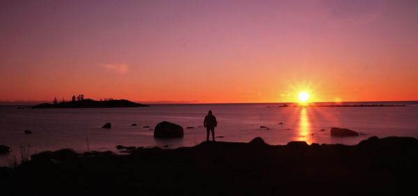 Silhouette people on beach against sky during sunset