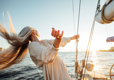 Senior woman standing at sailboat in sea