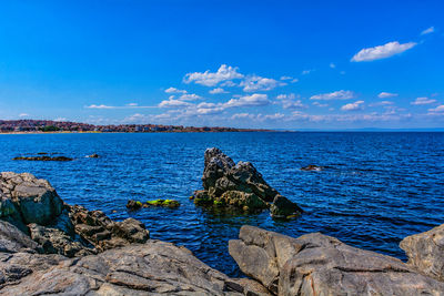 Scenic view of rocks in sea against blue sky