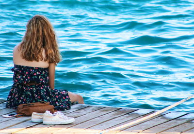 Rear view of woman sitting by swimming pool