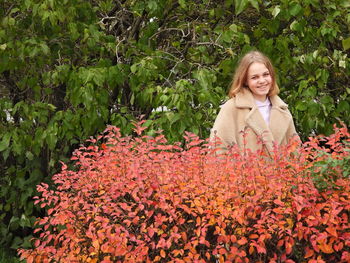 Portrait of a smiling young woman by plants