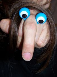 Cropped image of hand with artificial eyes and hair