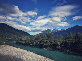 Scenic view of river by mountains against sky