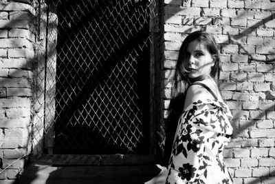 Portrait of confident woman standing against brick wall