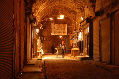 Illuminated street amidst buildings in city at night