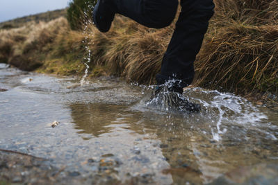 Low section of person running in puddle