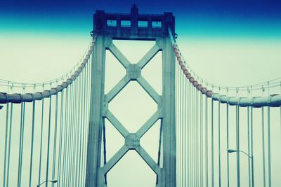 Low angle view of suspension bridge against blue sky