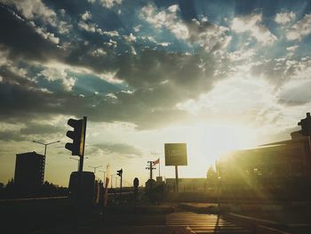 Silhouette city street against sky during sunset