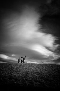 Person standing on field against cloudy sky