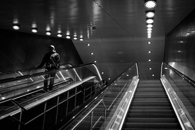 Man on escalator at illuminated railroad station