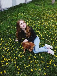 High angle view of teenage girl with eyes closed sitting by dog on grassy land