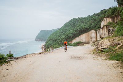 Rear view of man walking on beach against sky