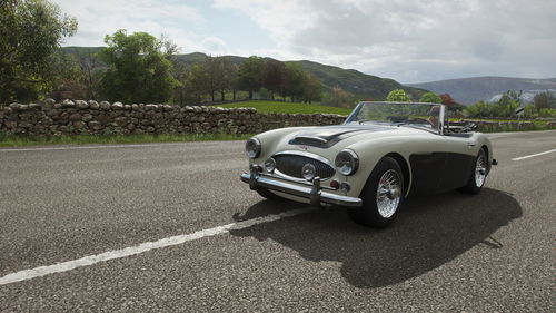 Vintage car on road against cloudy sky