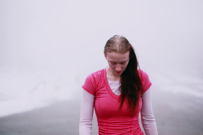 Young woman standing against sky