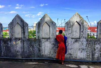 Rear view of woman standing by buildings against sky