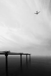 Low angle view of airplane flying over sea against sky