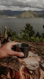 Midsection of person holding ice cream against mountains