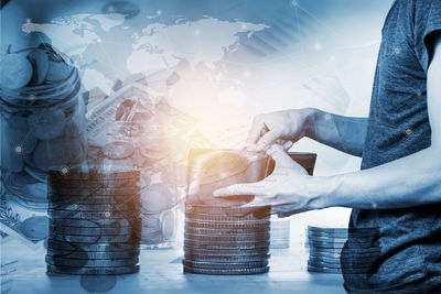 Multiple exposure of man with wallet stacked coins and world map